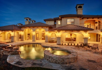 Luxury Mediterranean home with backyard pool at night, typical of Steiner Ranch, West Austin